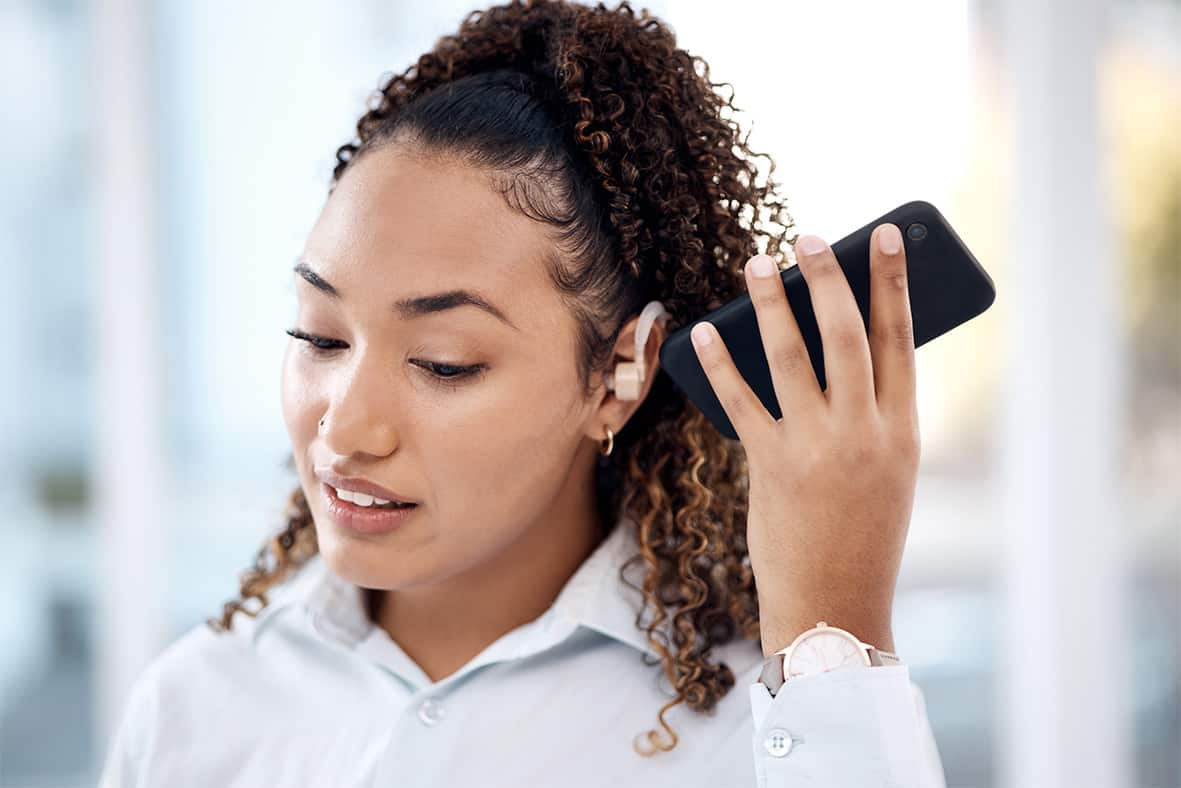  woman with a hearing aid holding a smartphone to her ear