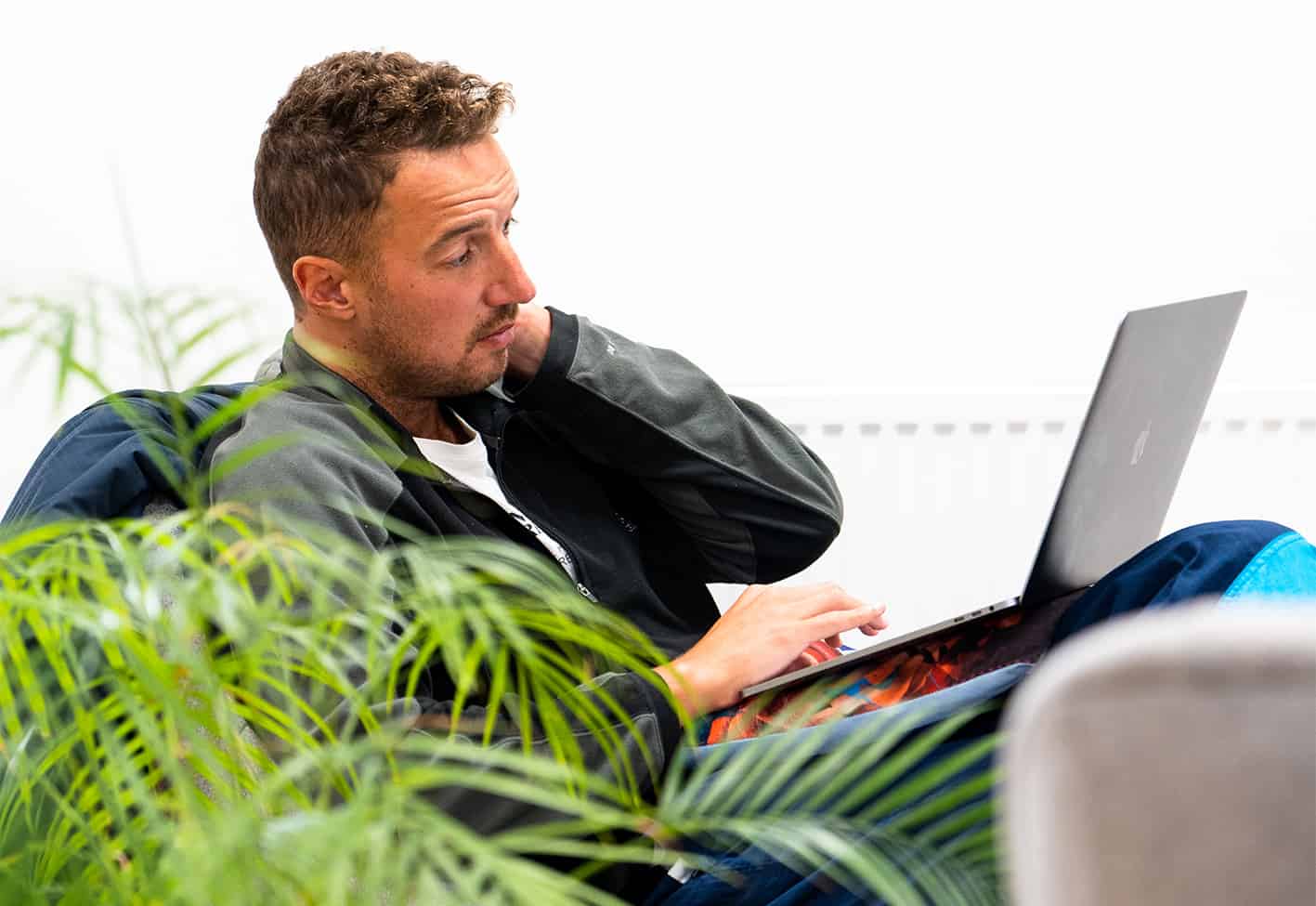 man sitting in a chair looking at a laptop