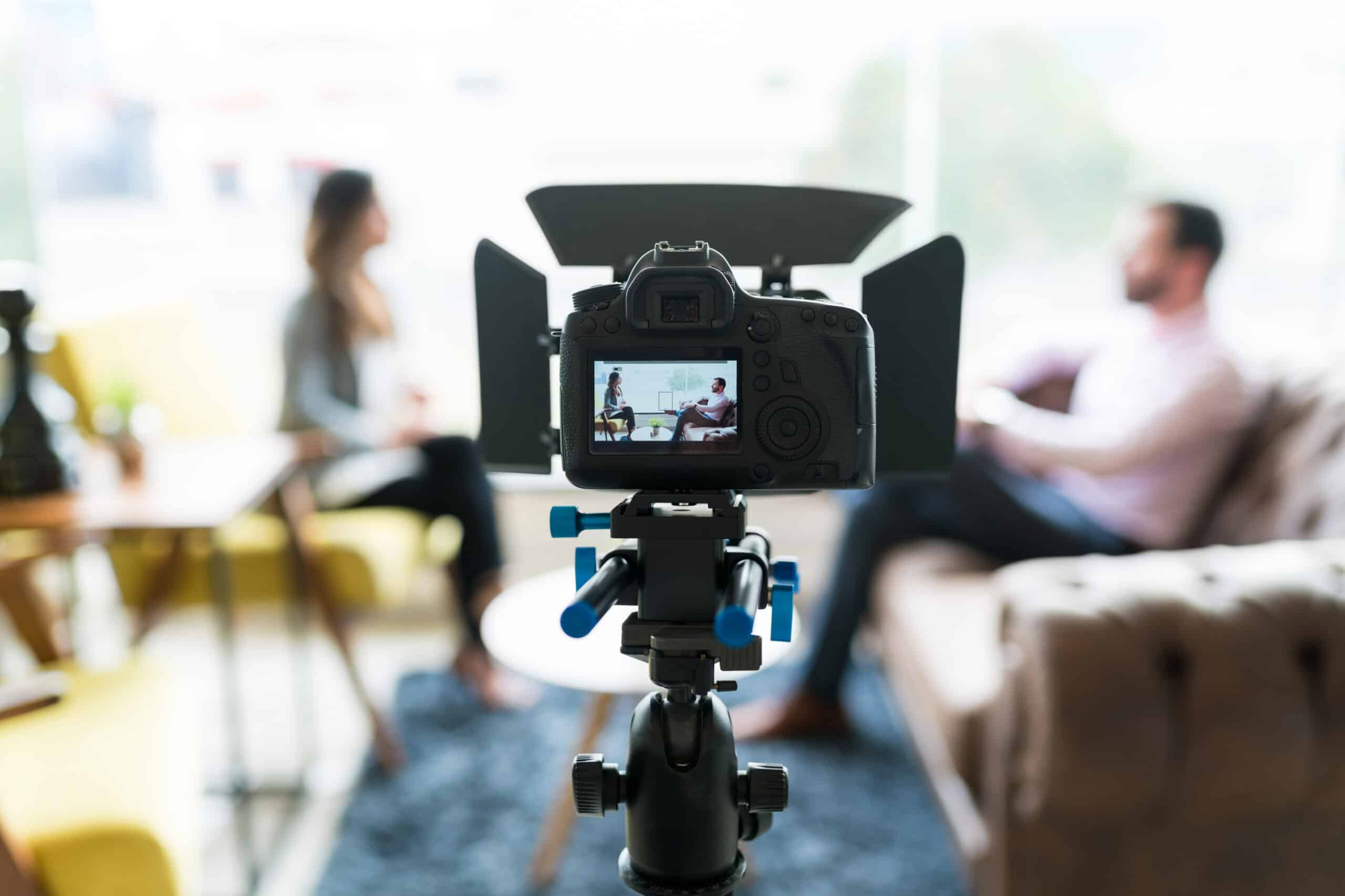 camera pointing at seated people in the background