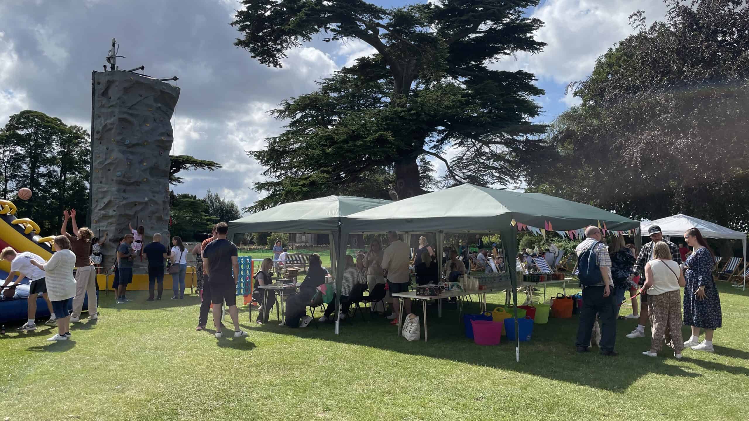 people eating and drinking at the summer party with climbing tower in the background